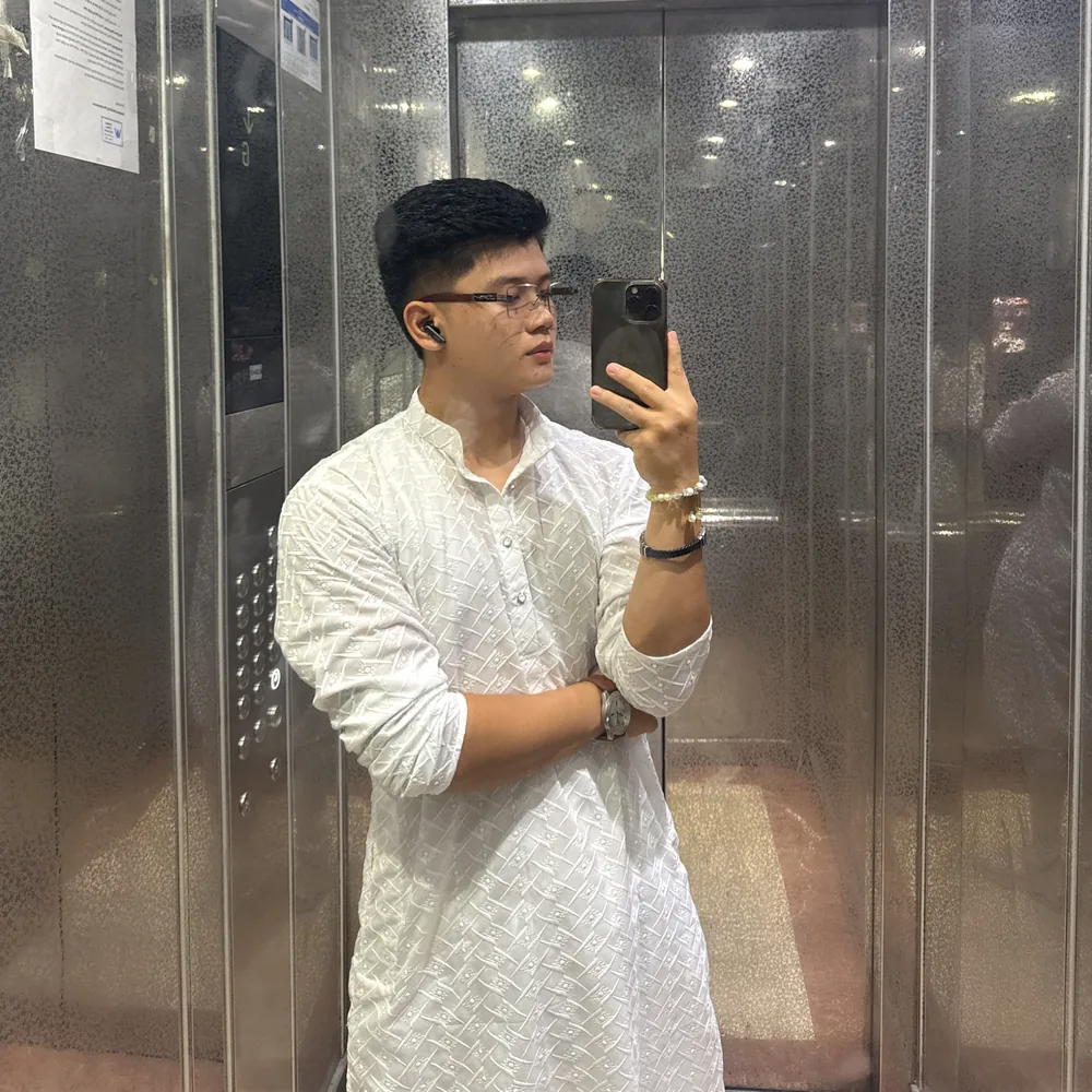 Tenzy in a white outfit, taking a mirror photograph in an elevator